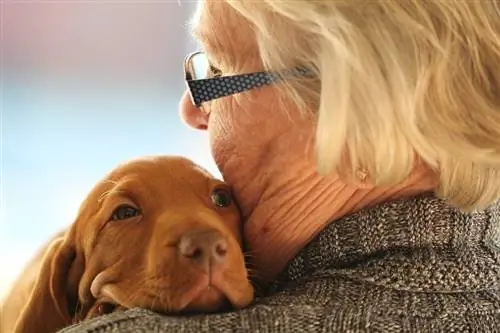 mwanamke mzee akimkumbatia mbwa wa Vizsla