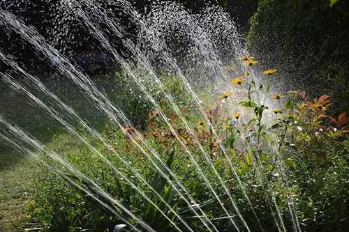 aspersor de água de jardim perto de um canteiro de flores