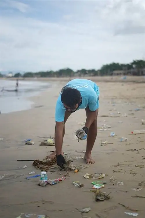 seorang pria mengambil sampah plastik di pantai