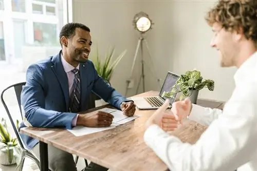 mans sit aan tafel en glimlag en bespreek versekering