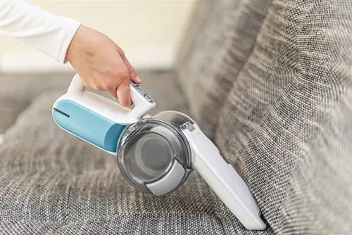 isang babaeng nagva-vacuum ng mga kasangkapan sa isang bahay gamit ang isang hand-held portable vacuum cleaner