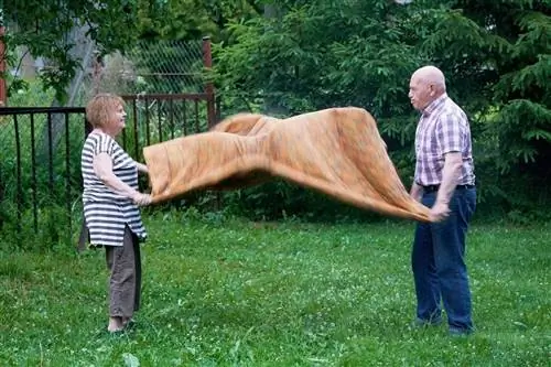 pareja de ancianos limpiando una manta afuera