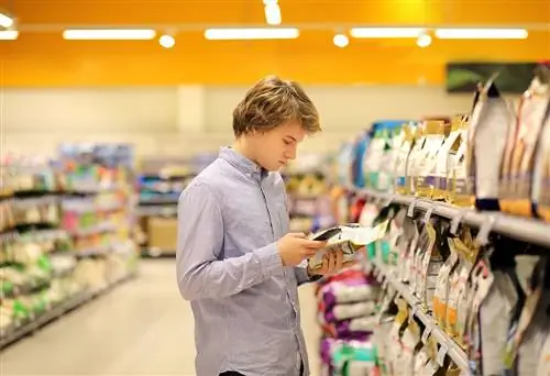 Lalaking namimili sa supermarket na nagbabasa ng impormasyon ng produkto