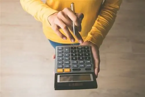 Mulher empreendedora usando uma calculadora com uma caneta na mão