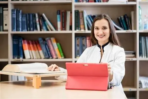 Medicinstuderende på biblioteket forsker i bøger og skriver resultater ned på sin bærbare computer